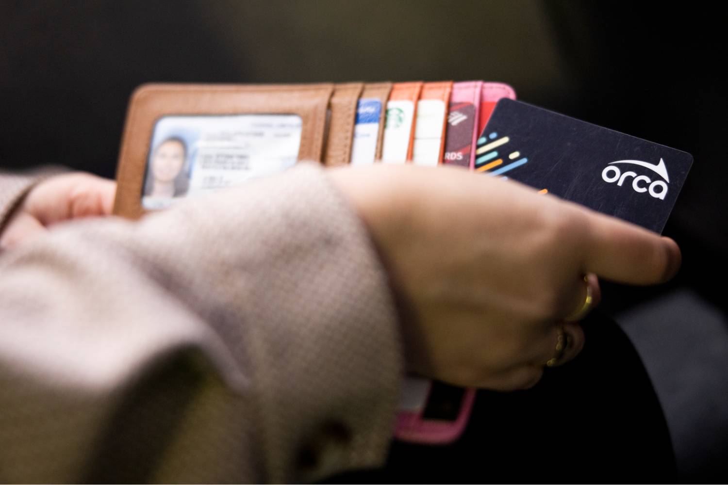 Close-up of a woman's hand pulling a black ORCA card from her wallet.