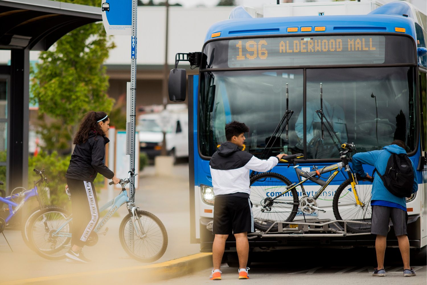 Three people load bikes on to the 196 bus. 