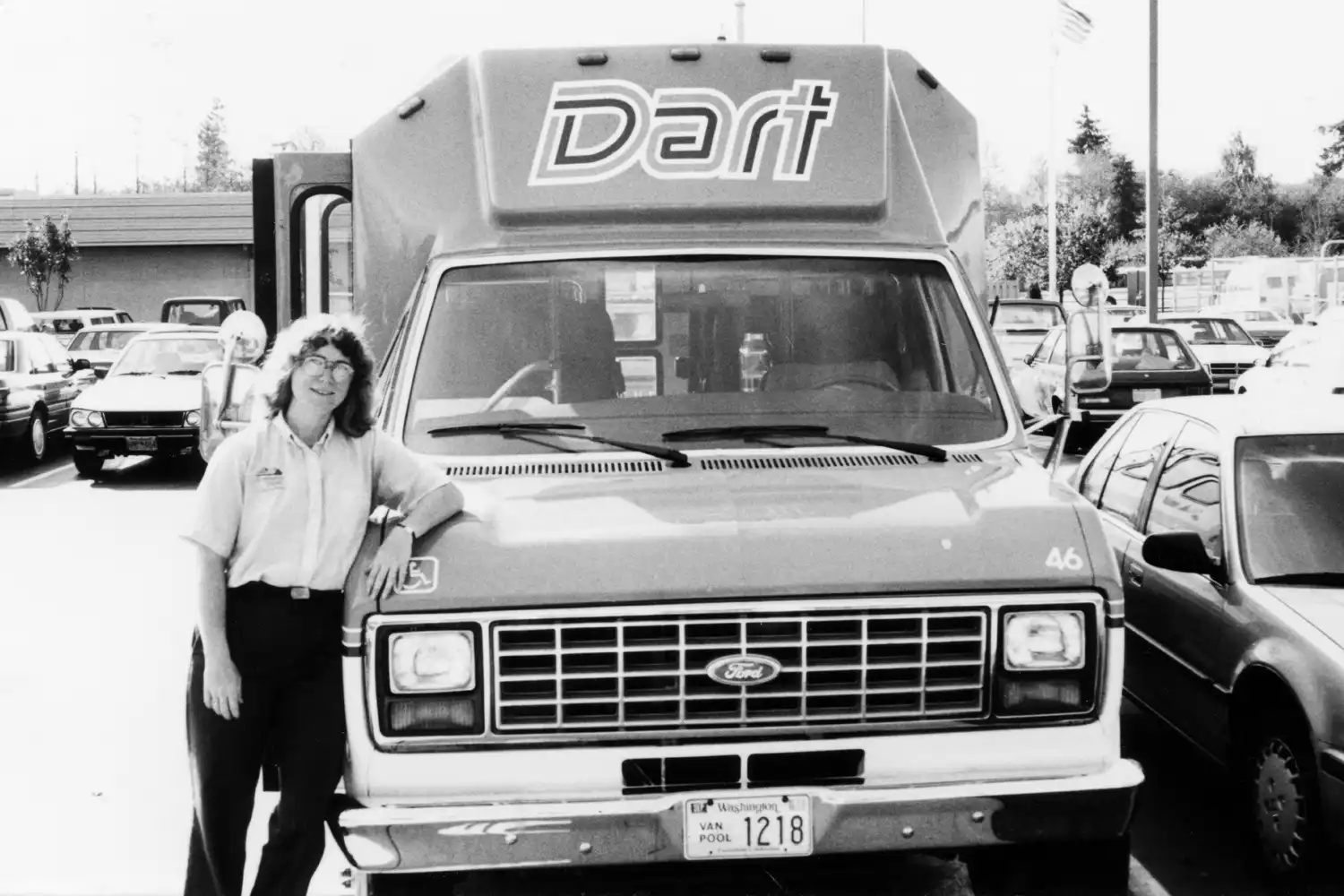 50th Anniversary Timeline a black-and-white photo of a driver posing next to an old DART vehicle