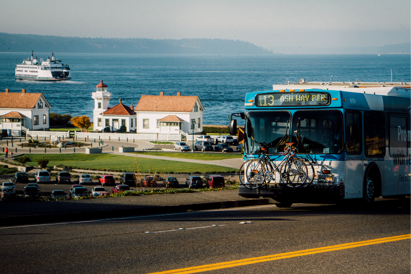 A Route 113 Community Transit bus with Mukilteo Lighthouse Park and a Washington State ferry in the background.