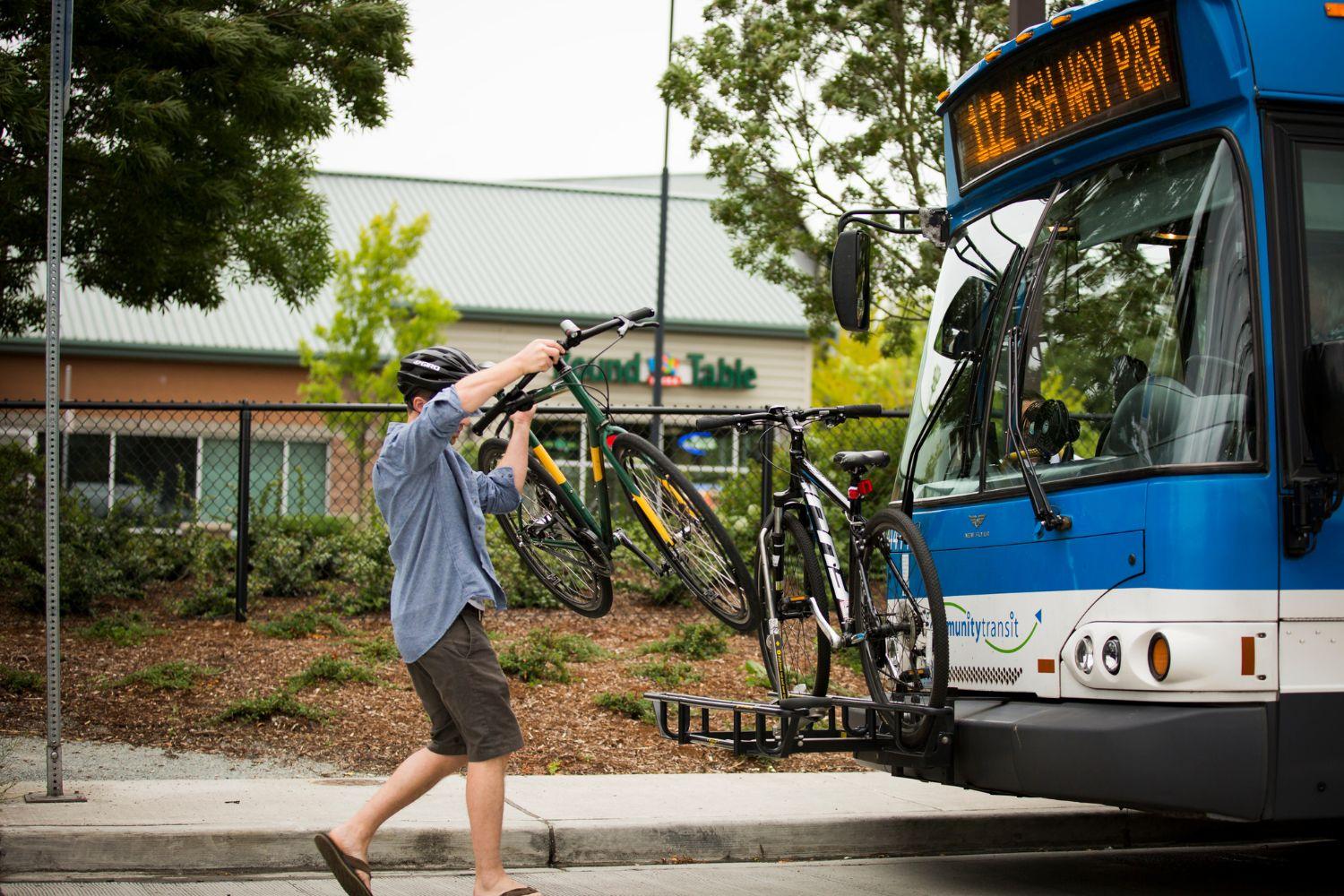 A man loading his bike onto a bus bike rack. 