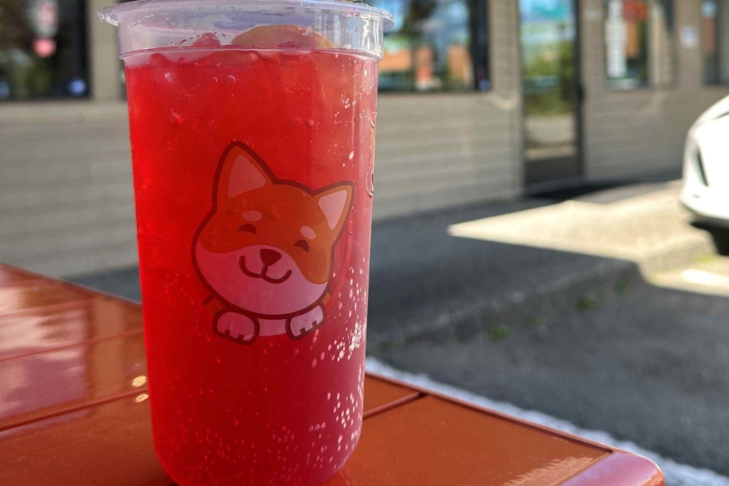 A picture of a cup of bubble tea. There is an orange and white dog printed on the side of the cup.