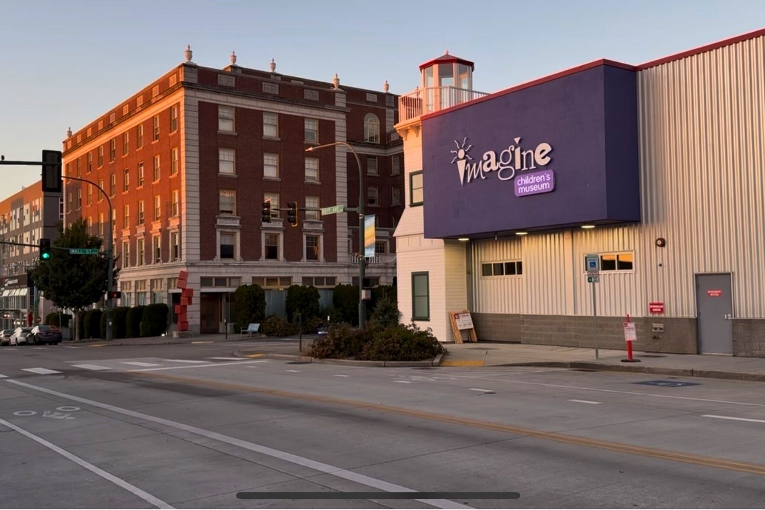Street view of Imagine Children’s Museum building with a lighthouse feature, next to a tall brick building.
