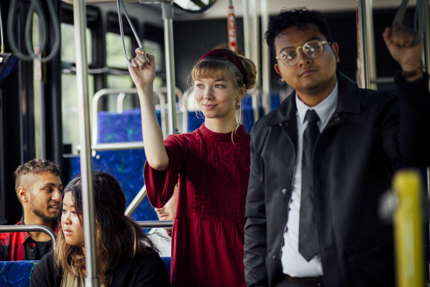 Various people standing and sitting as they ride a bus