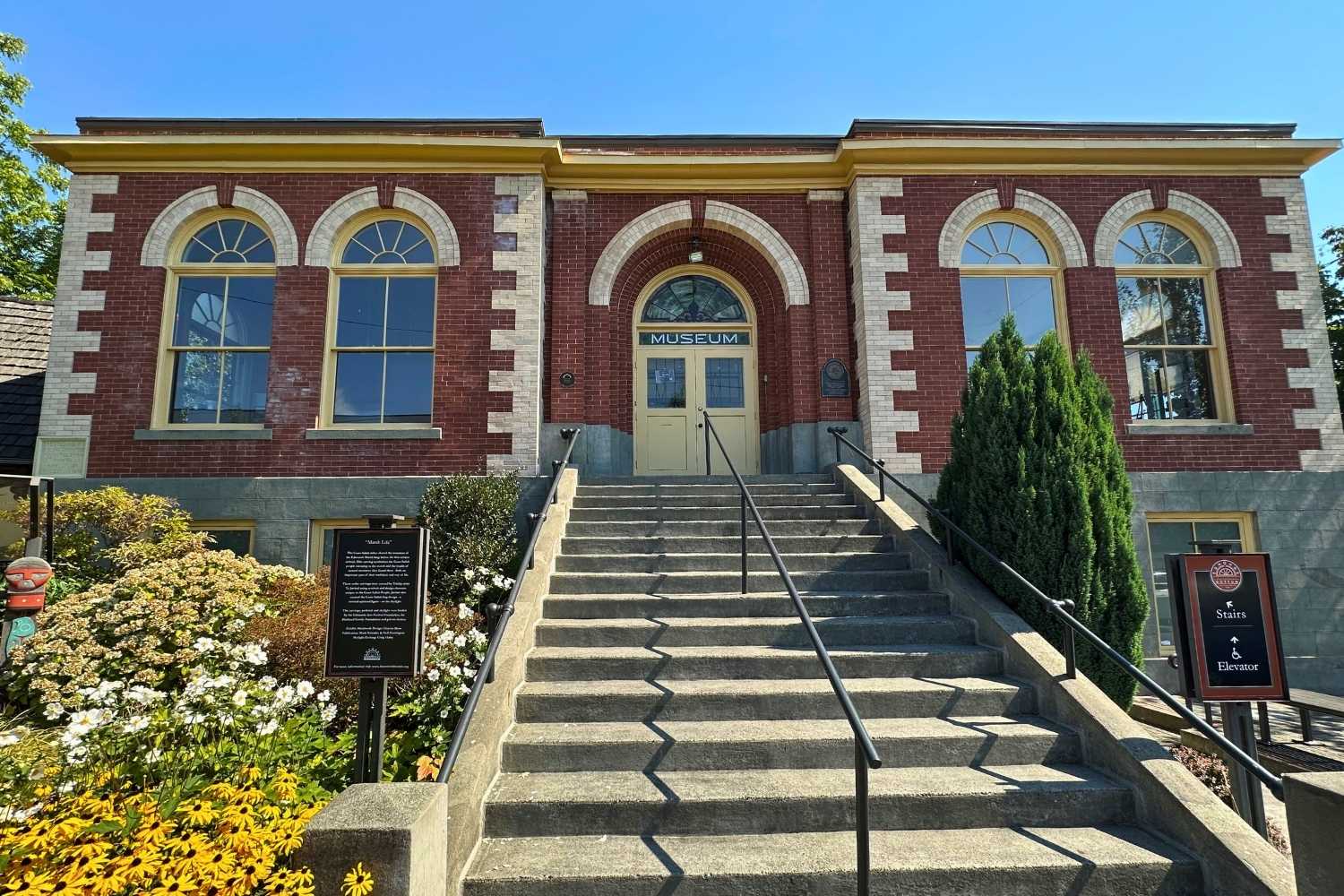 Brick museum building with arched windows and wide concrete steps leading to the entrance.
