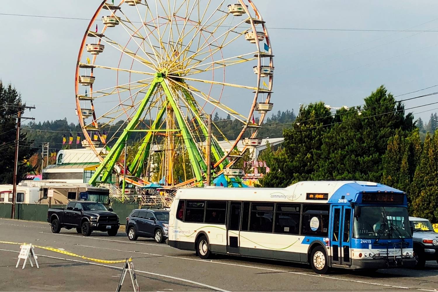 An image of a bus driving down the road. In the background is a ferris wheel.