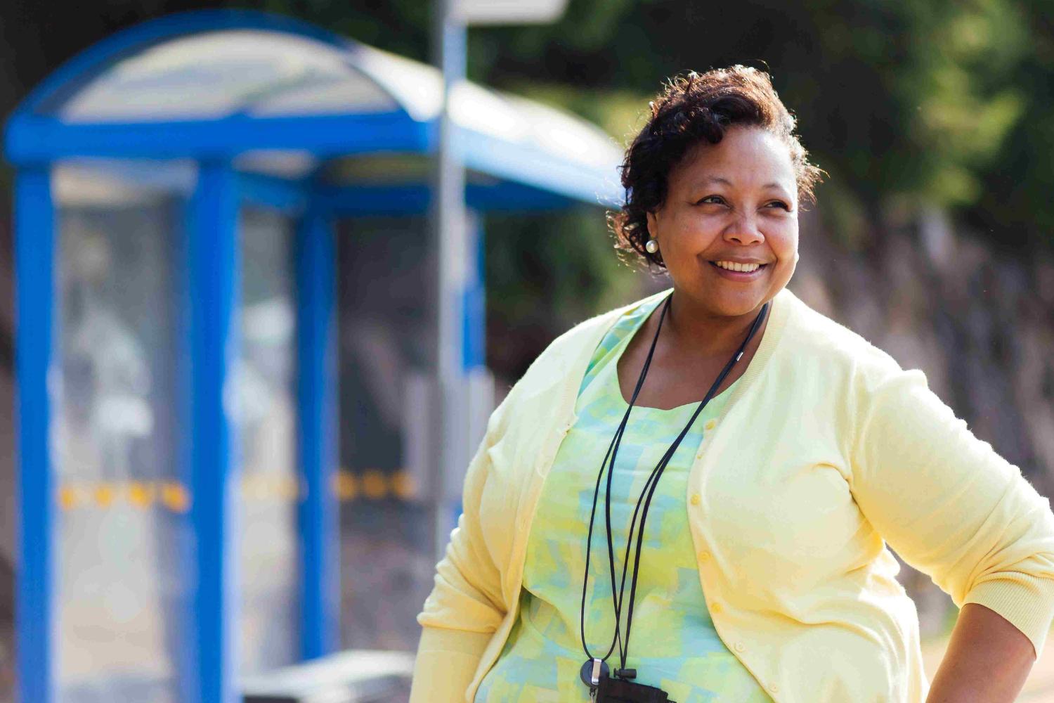 A woman smiling while standing in front of a Community Transit bus stop. 