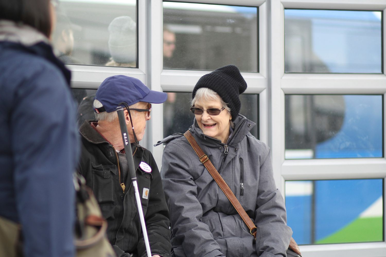 Older adult riders smile while waiting for their bus. 