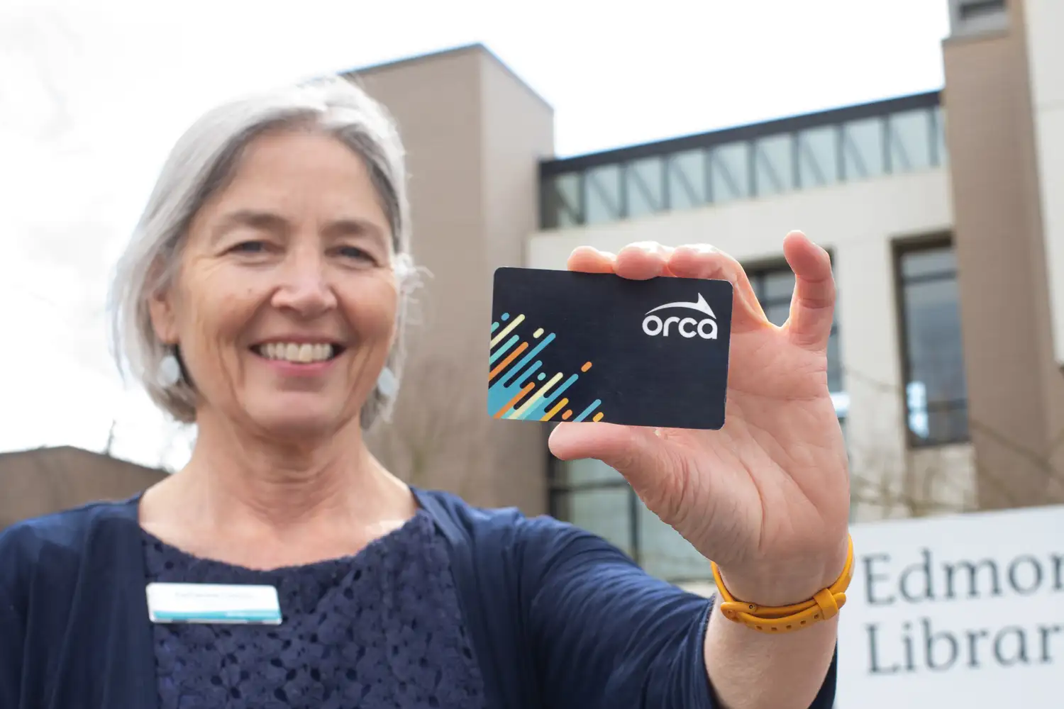 a woman holding up and ORCA card and smiling