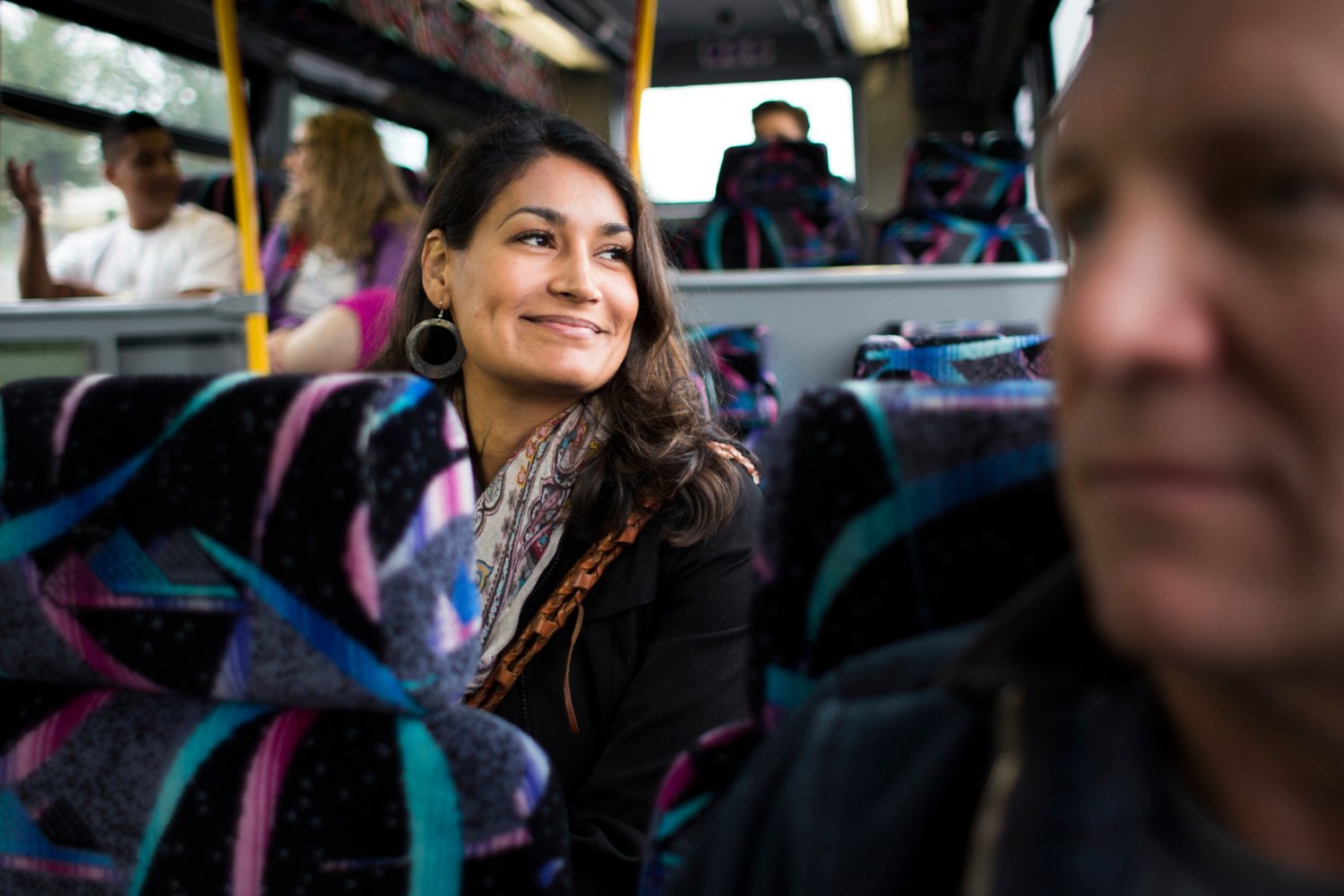 A woman riding the bus with a pleasant expression on her face.