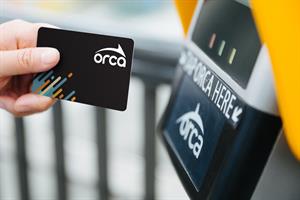 A rider taps their new black ORCA card at a card reader
