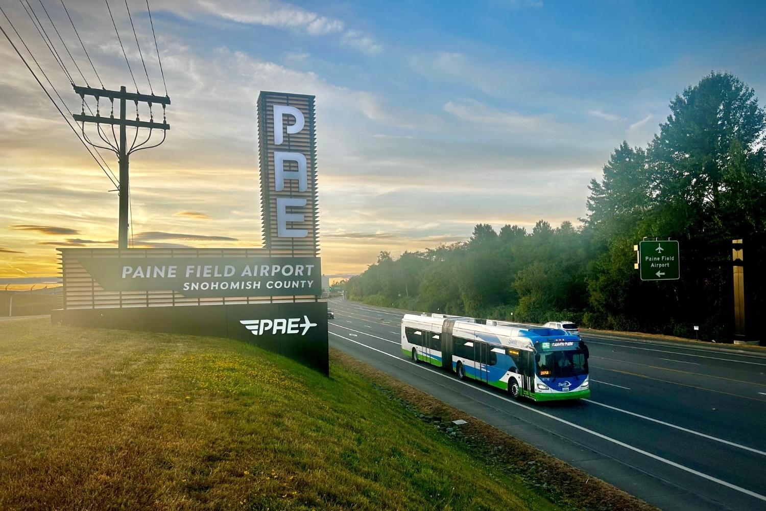 A picture of a Swift Green bus passing by the Paine Field Airport sign.