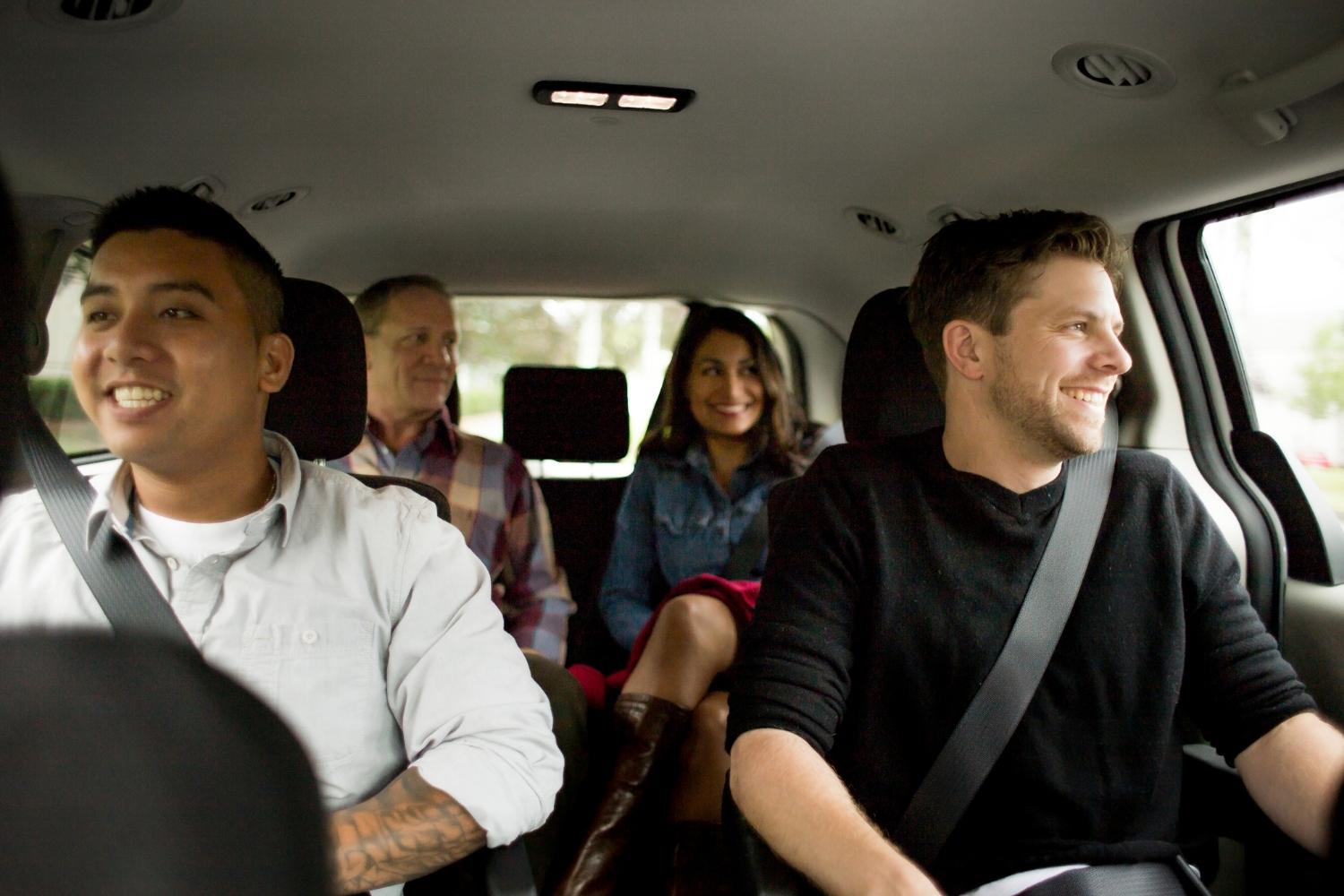 A group of people are sitting together in a car and talking.