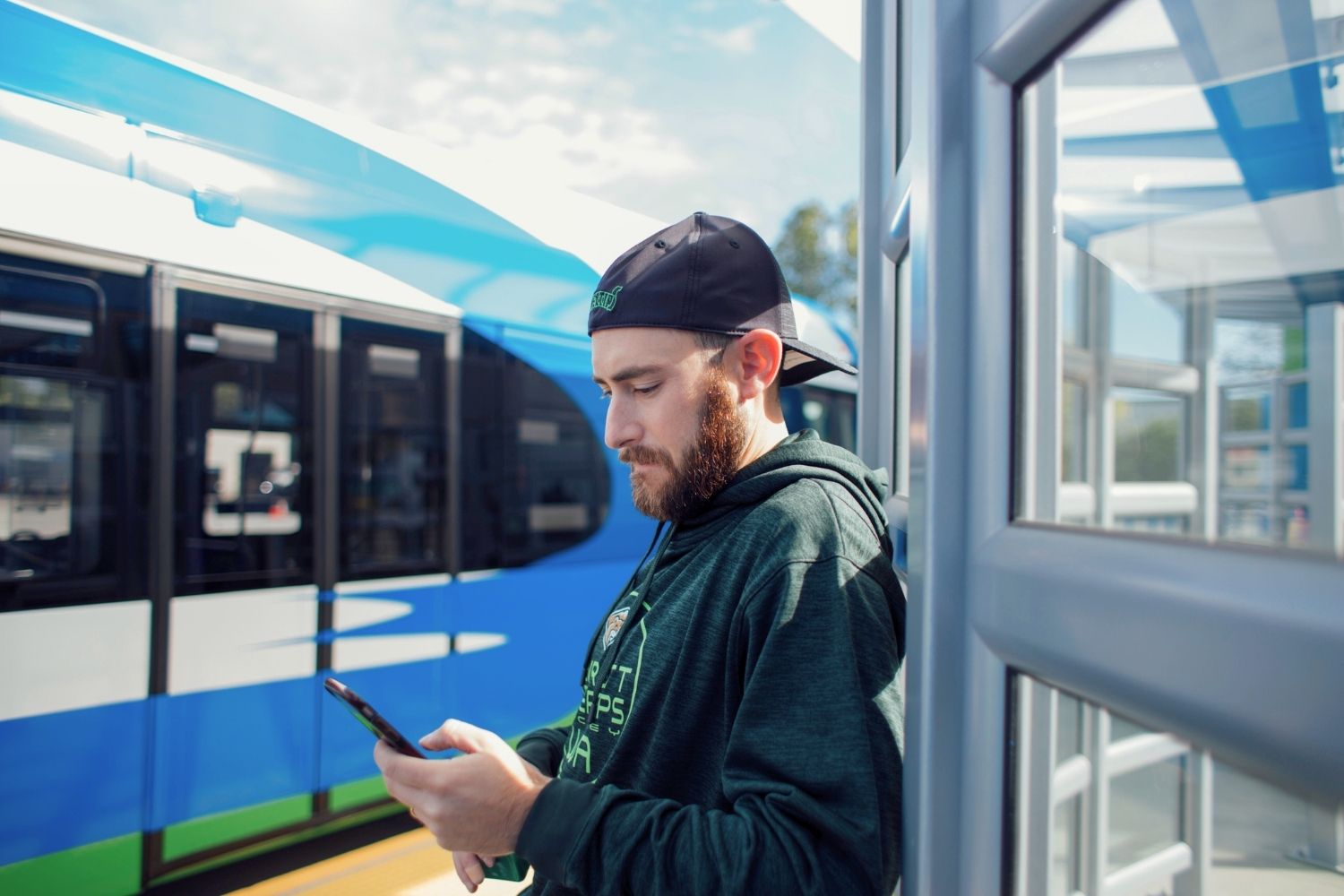 A photo of a man standing at a Swift Station checking his phone.