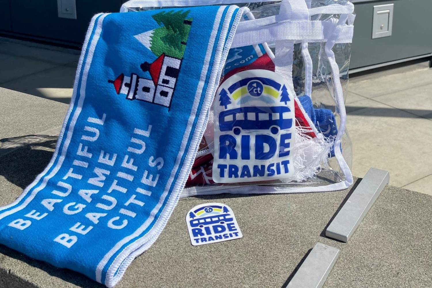 Prize Pack an image of a scarf in a clear back with a sticker sitting on a curb outside of the ride store