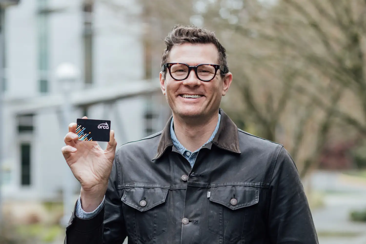 a small business owner smiling while holding up an ORCA card