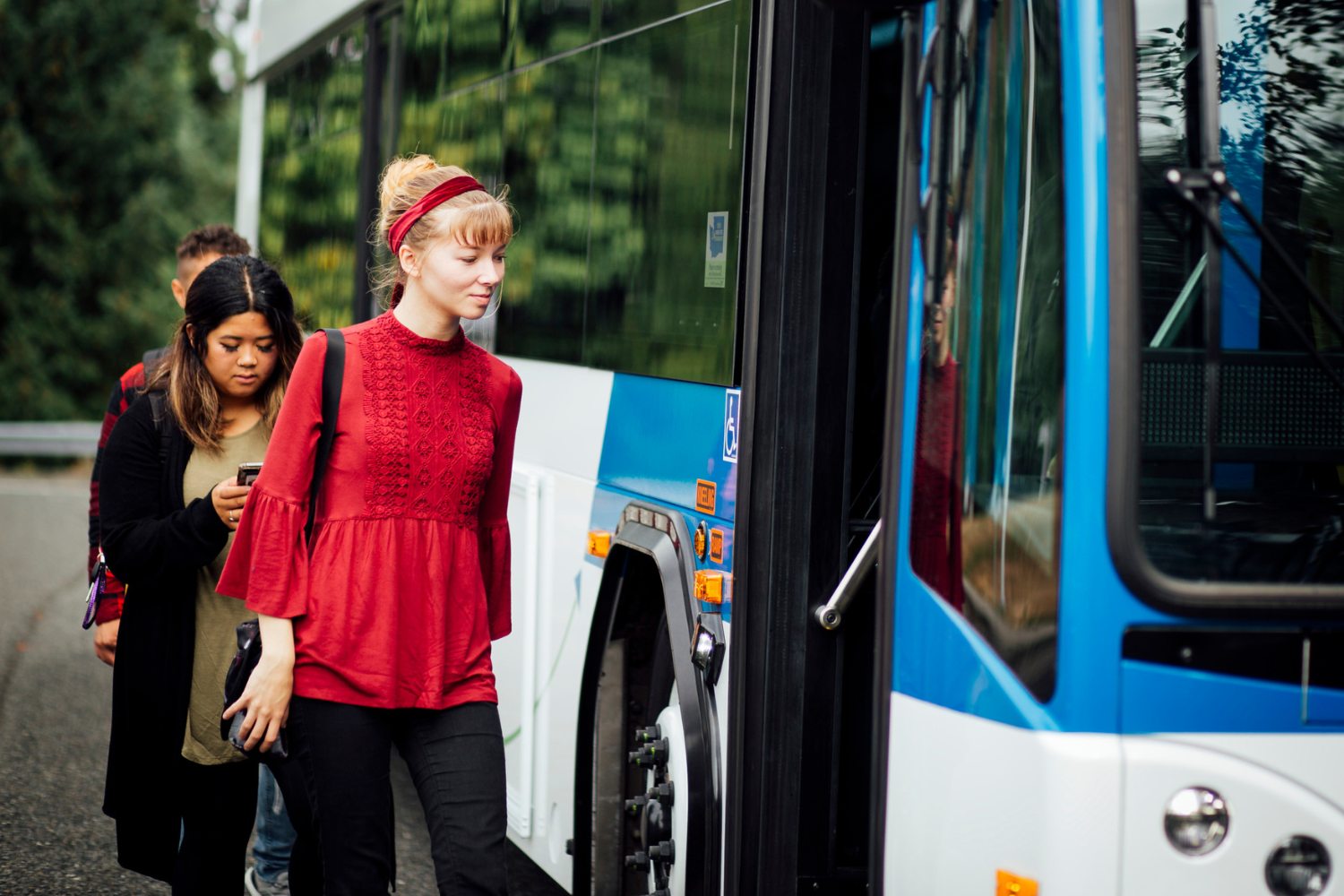 Three people walking on to a bus. 