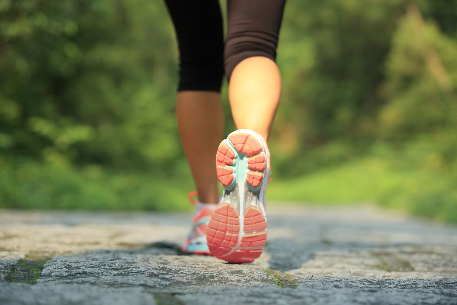 An image of the back of someone's tennis shoe as they walk down a trail.