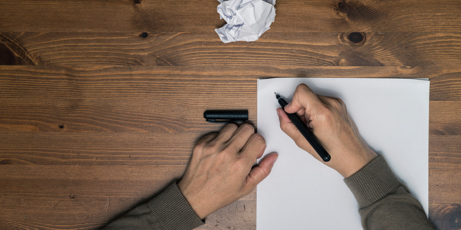 Picture of man's hands attempting to write a letter.