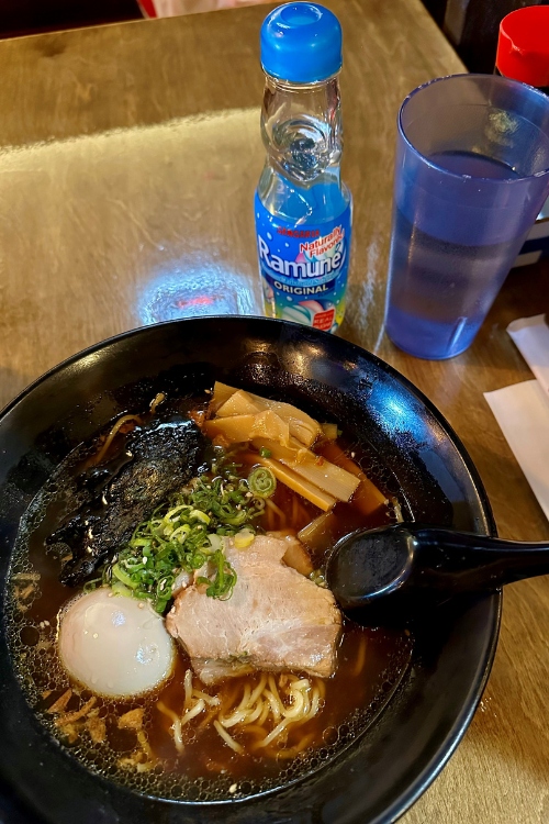 A bowl of park ramen and a bottle of ramune. 