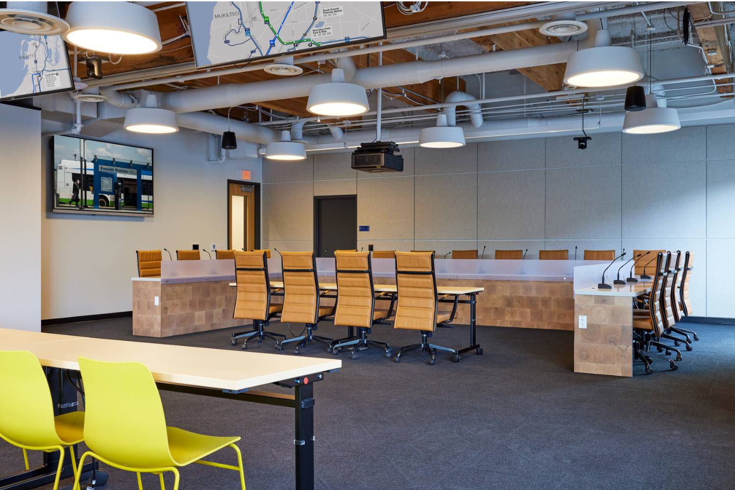 CT Board Room set-up for meeting. High-backed leather chairs surround dais. Bright yellow chairs for audience.