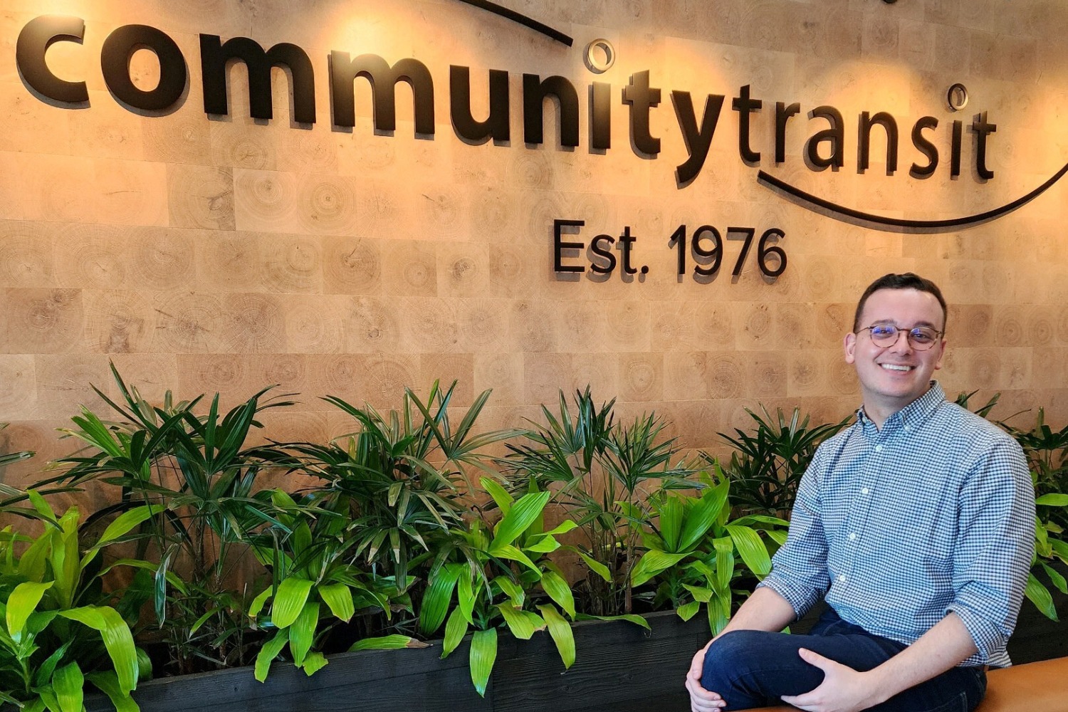 A man with dark hair and glasses sits on a sofa in the lobby of Community Transit's admin building.