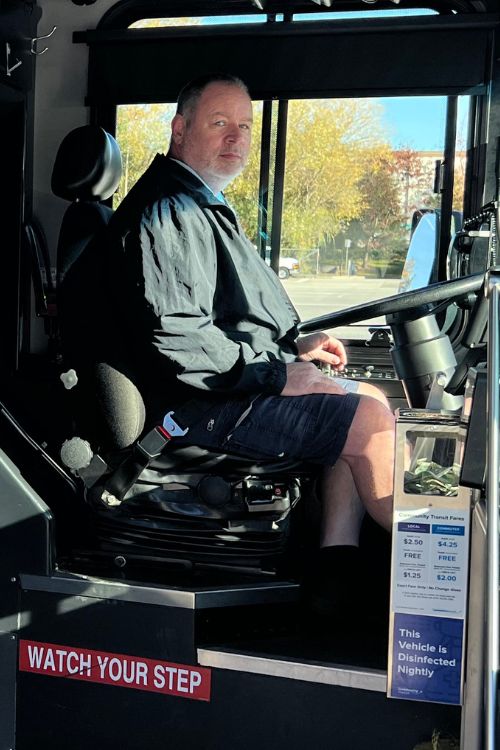 A male coach operator sits in the driver's seat of a Community Transit bus