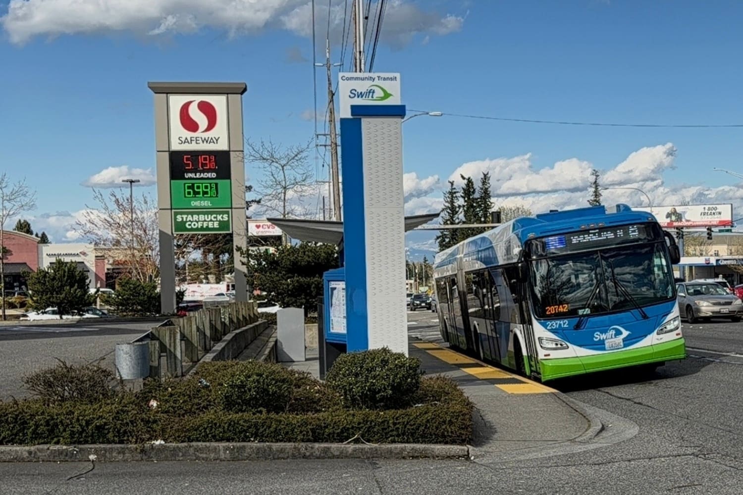 A Swift bus stops at the 148th St Station. A Safeway gas station sign next door advertises unleaded gas at more than $5 a gallon.