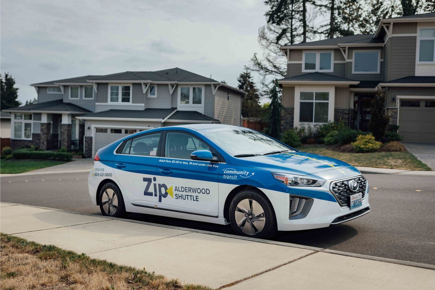 A Community Transit Zip Shuttle car is parked on a residential street.