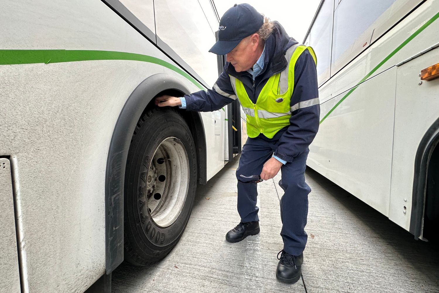 A Community Transit Coach Operator checking tire pressure on a bus. 