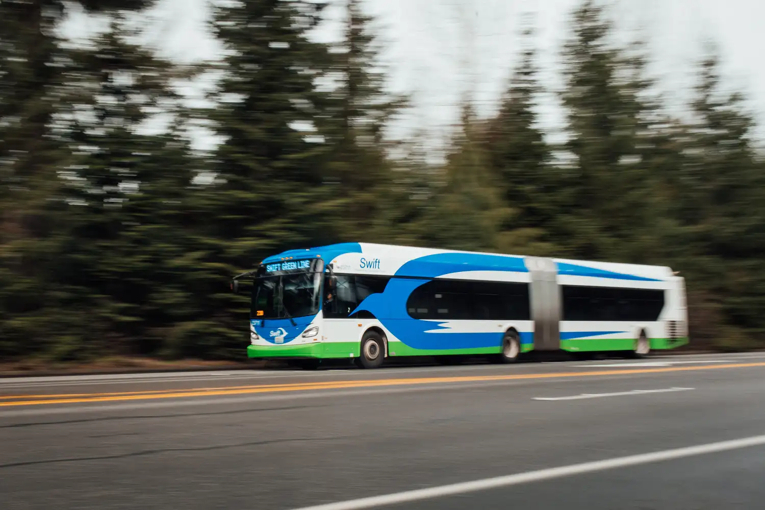 A Swift Green Line bus is driving along a highway.