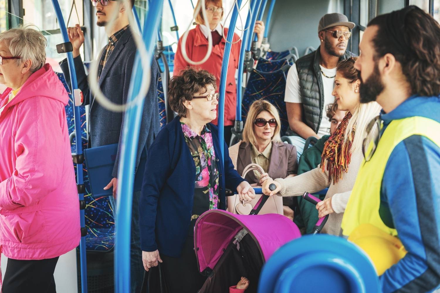 Diverse group of riders, including seniors and a parent with a stroller, riding a public transit bus.”