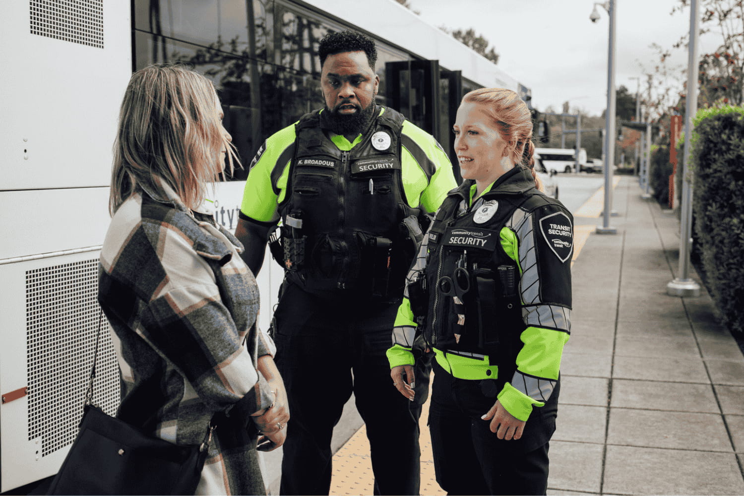 A woman talks with Transit Security Officers next to a Community Transit bus