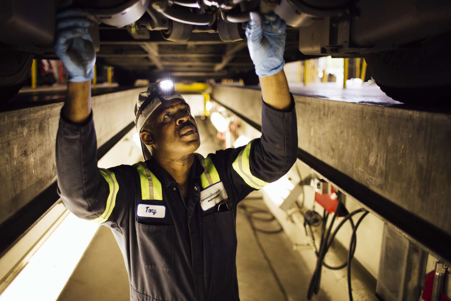 A mechanic works in a clean and well-lit space beneath a CT vehicle.