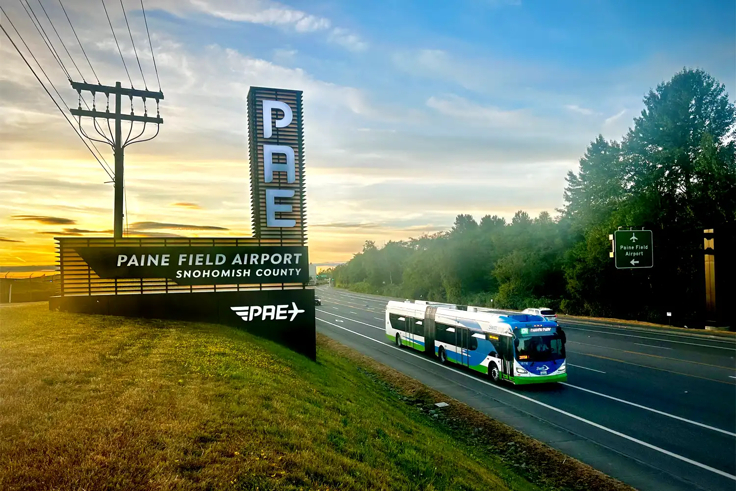 a Swift Green Line bus passing by the Paine Field Airport sign at sunrise