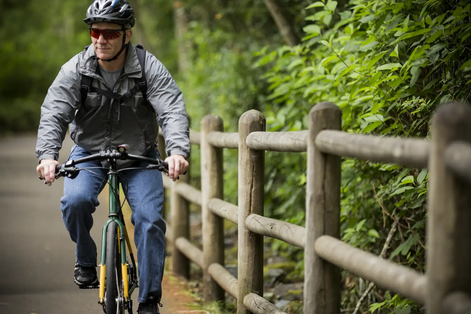 a person riding a bike on a trail next to a wooden fence