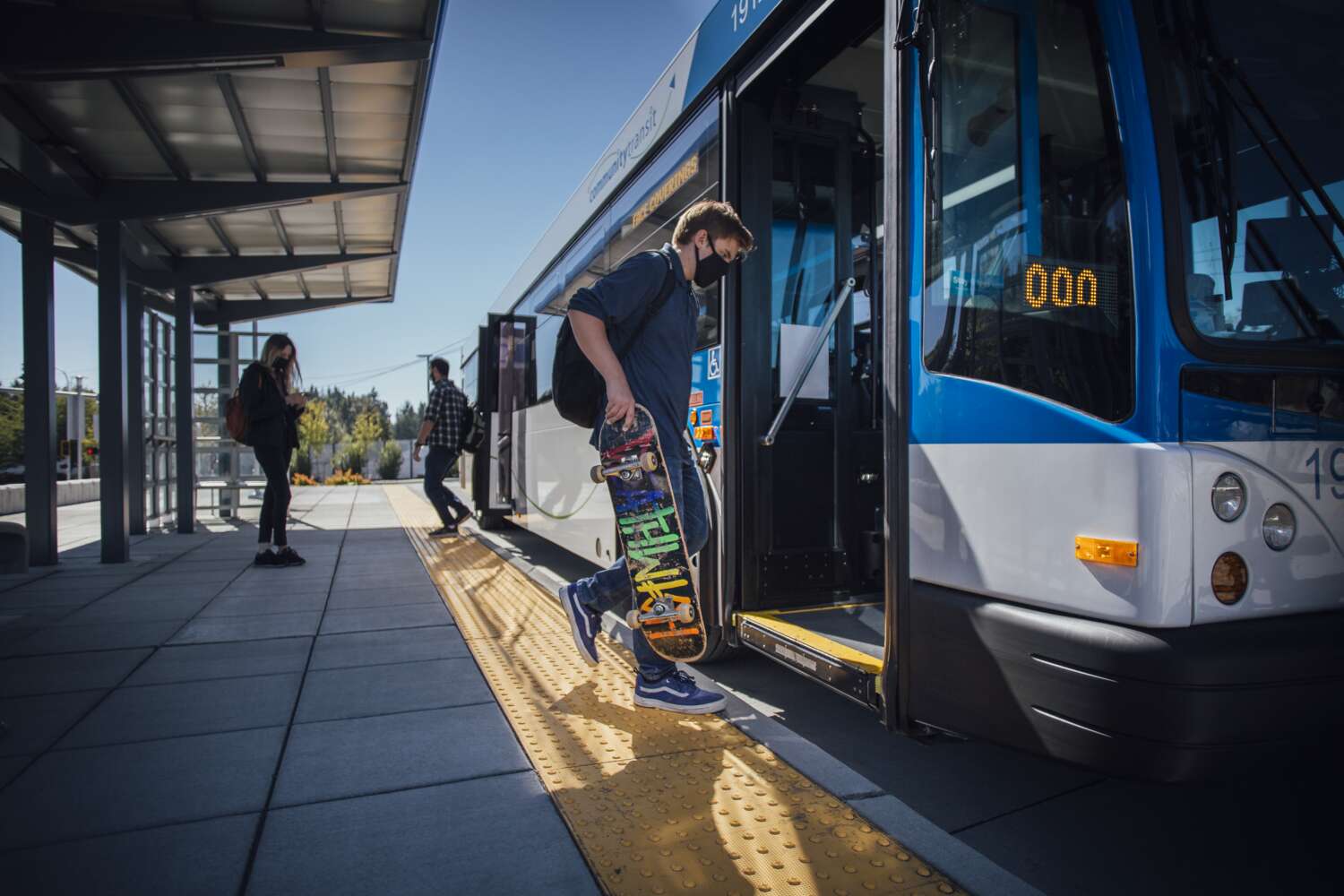 Young man with a skateboard enters a Community Transit bus
