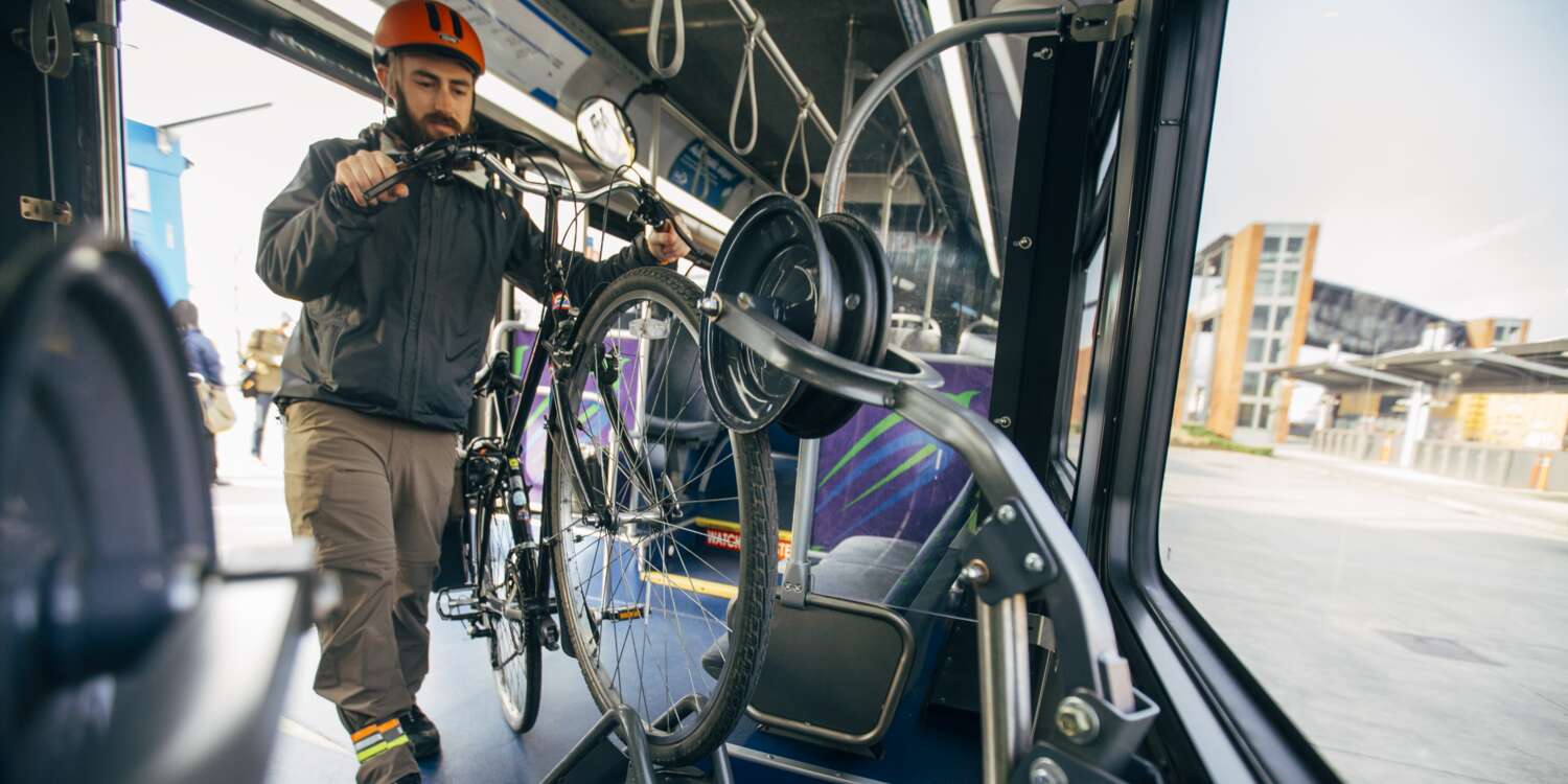 A person rides a bus while holding his bike helmet.