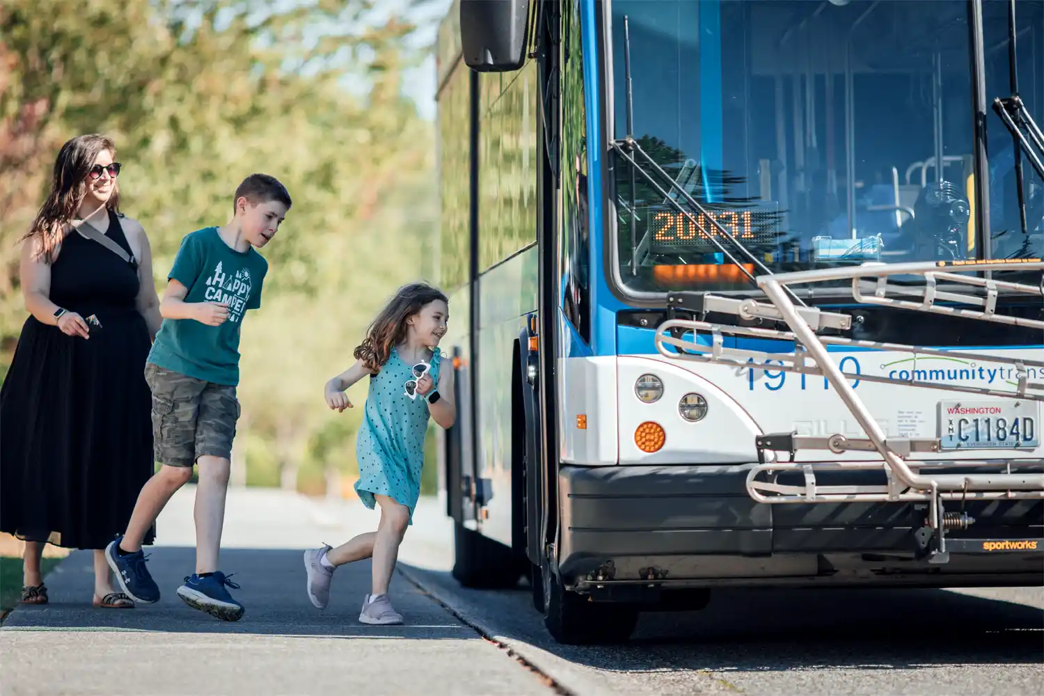 two children and their parent excitedly boarding a bus
