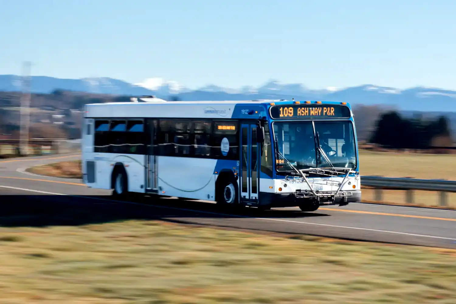 a local service bus driving on a road through a field