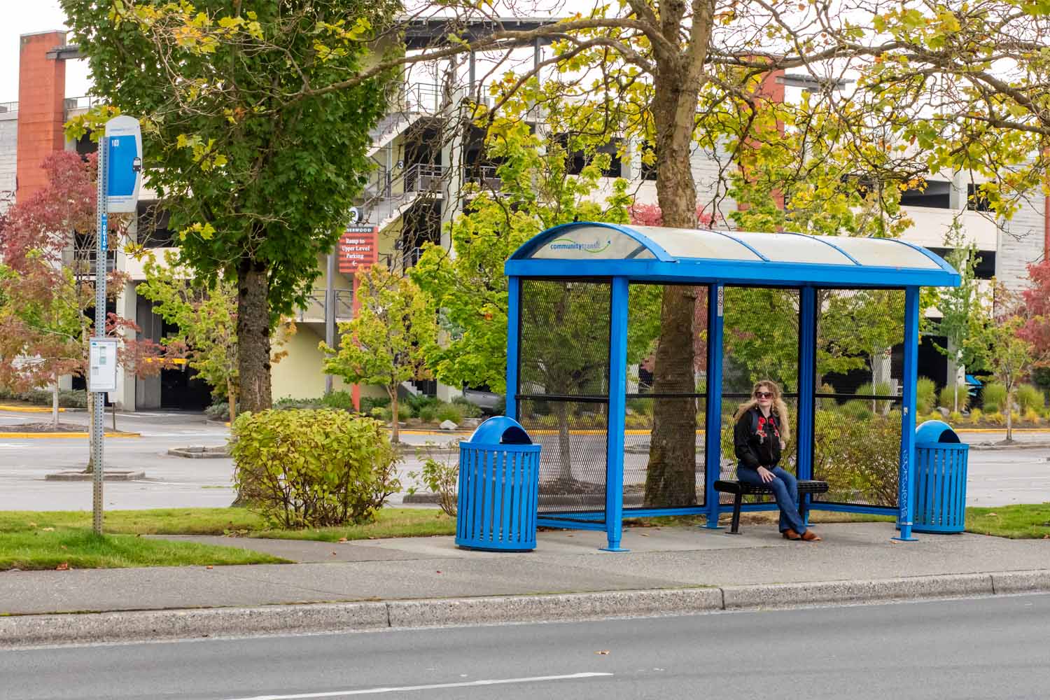 a rider sitting at a bus stop with a shelter waiting for a bus