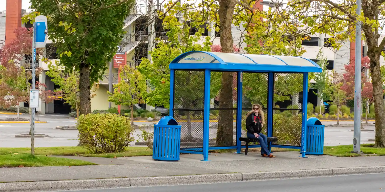 a rider sitting at a bus stop with a shelter waiting for a bus