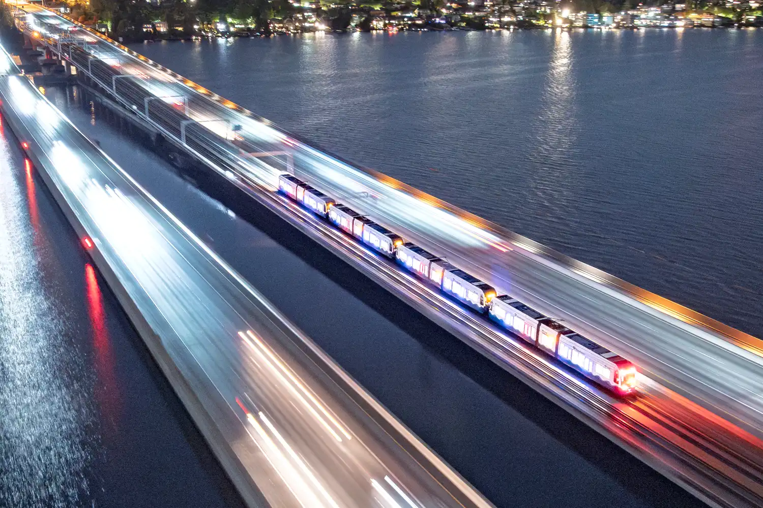 a Link light rail train traveling across the I-90 floating bridge at night