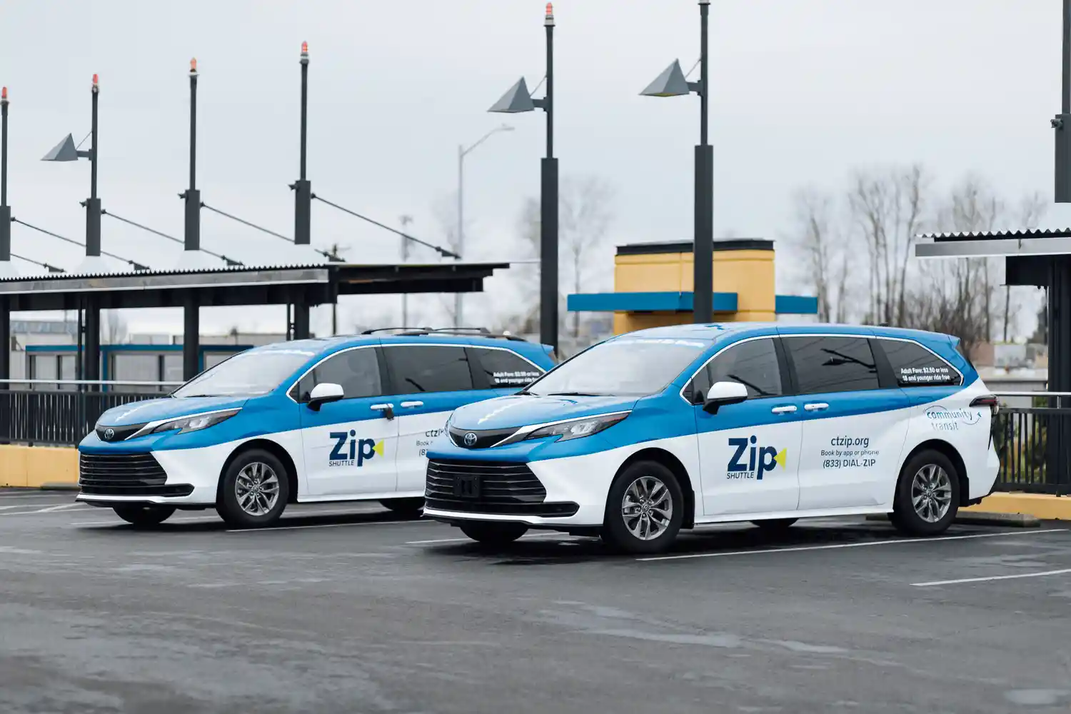Two Zip Shuttle rideshare vans parked at a tranist center
