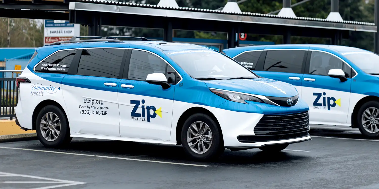 two Zip Shuttle vans parked next to each other
