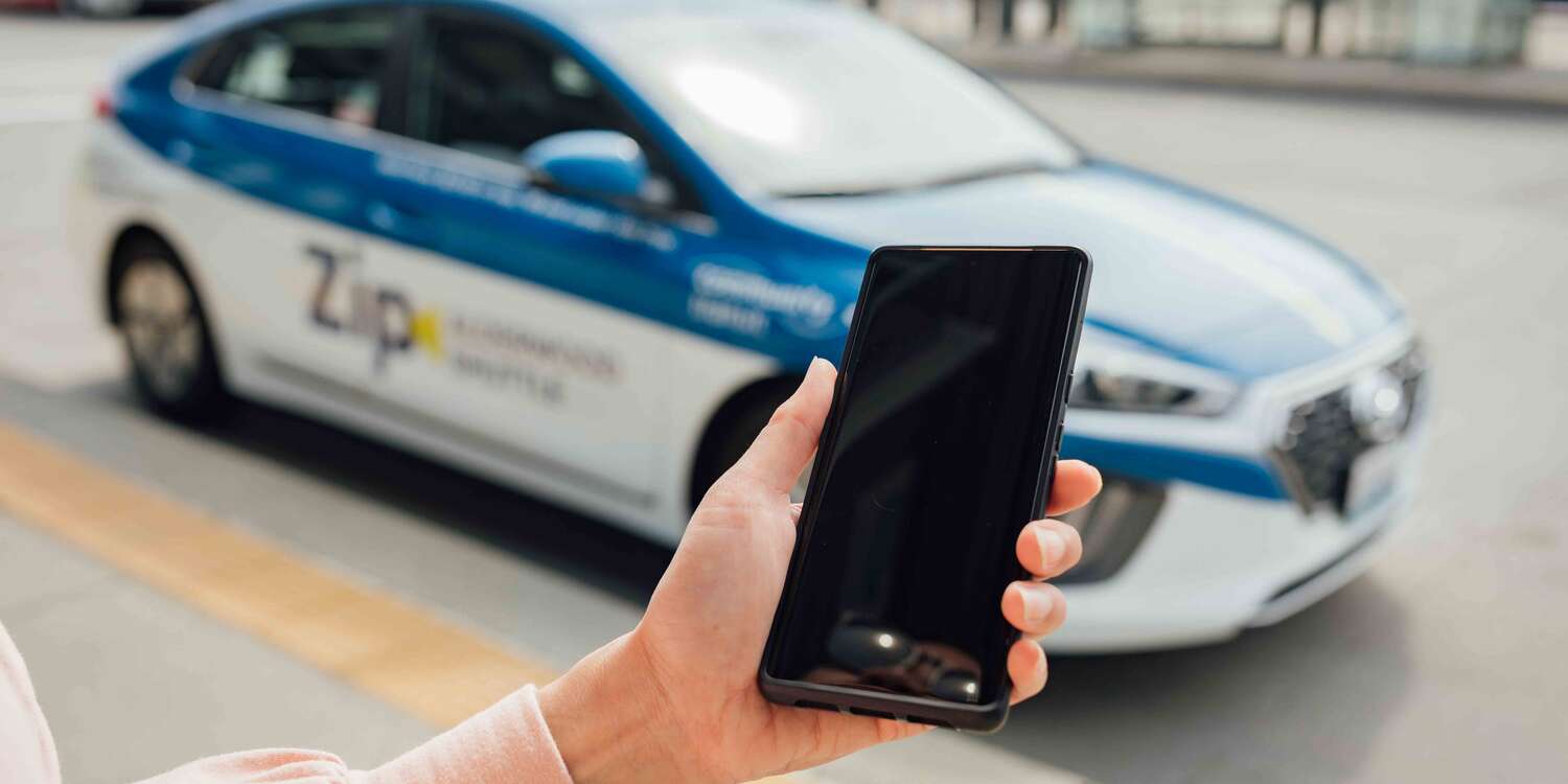 Rider using a phone to schedule a zip shuttle